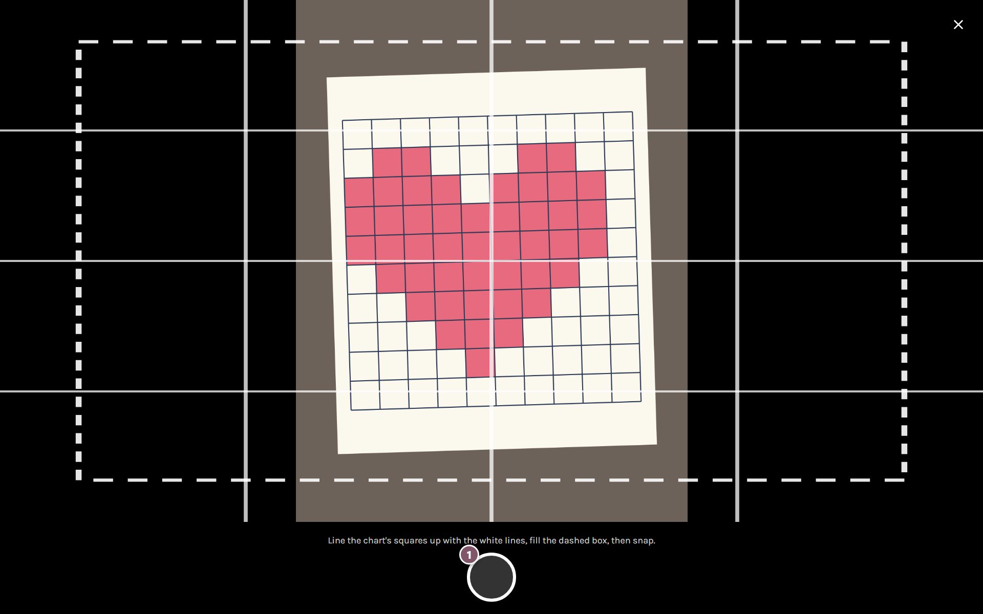 The camera with its white guide lines over a heart drawn on graph paper, and the shutter button marked 1 (on a computer)