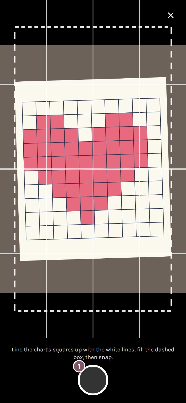 The camera with its white guide lines over a heart drawn on graph paper, and the shutter button marked 1 (on a phone)
